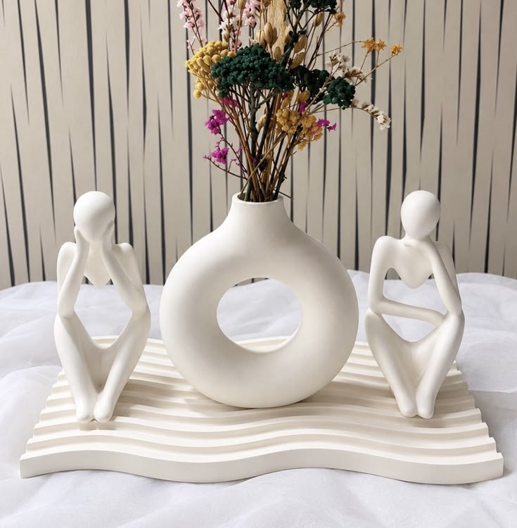 Zen fluted ripple tray holding two thinker figurines framing round donut vase with wild dried bouquet