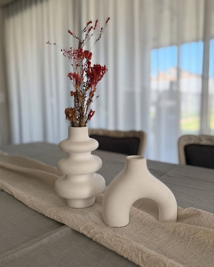 Dining table setup with modern ceramic vases and linen runner